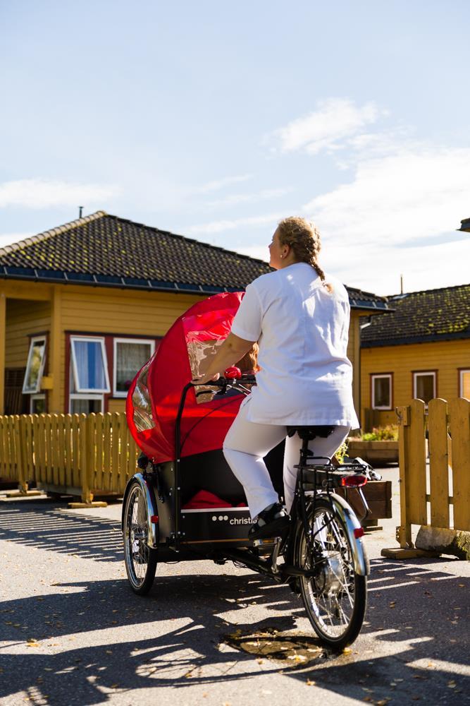 Pleier som sykler med pasient ute om sommeren - Klikk for stort bilde